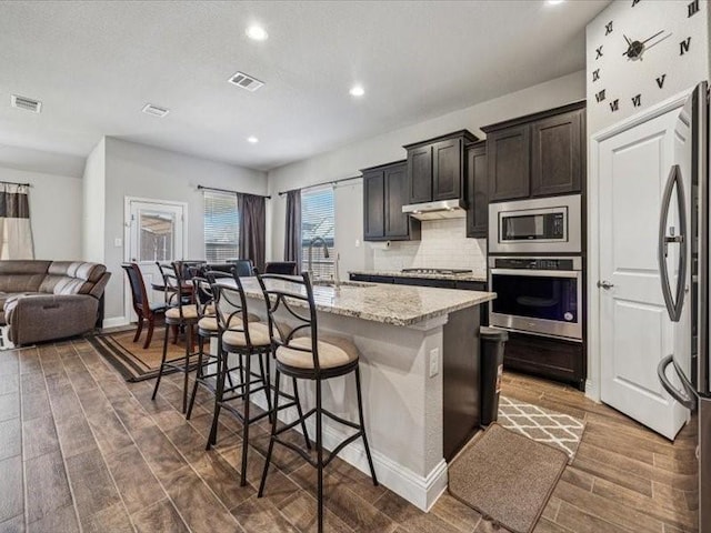 1044 Pitch Pine St, Hickory Creek, TX 75065 - kitchen with appliances with stainless steel finishes, open floor plan, a kitchen bar, a center island with sink, and tasteful backsplash