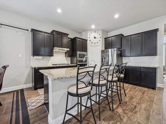 1044 Pitch Pine St, Hickory Creek, TX 75065 - kitchen with appliances with stainless steel finishes, wood finished floors, a kitchen island with sink, tasteful backsplash, and recessed lighting