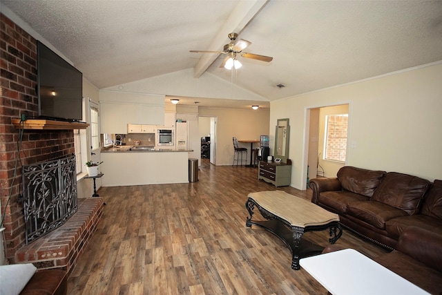 1217 Randy Dr, Graham, TX 76450 - living room with dark wood-style floors, a brick fireplace, ceiling fan, and a textured ceiling