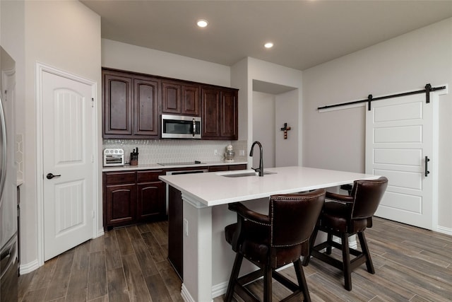 1705 Surrey Ct, Weatherford, TX 76087 - kitchen with appliances with stainless steel finishes, a sink, a barn door, light countertops, and dark wood-style flooring