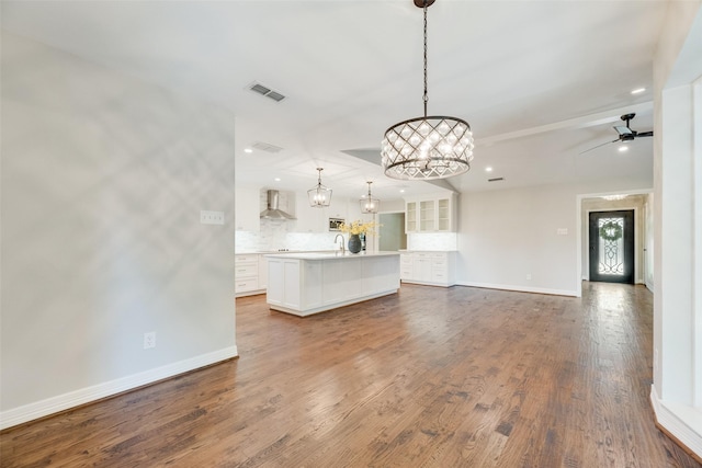 unfurnished living room with baseboards, a chandelier, recessed lighting, dark wood-type flooring, and a sink