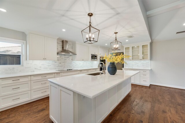 kitchen featuring wall chimney range hood, stainless steel microwave, a sink, black electric cooktop, and backsplash
