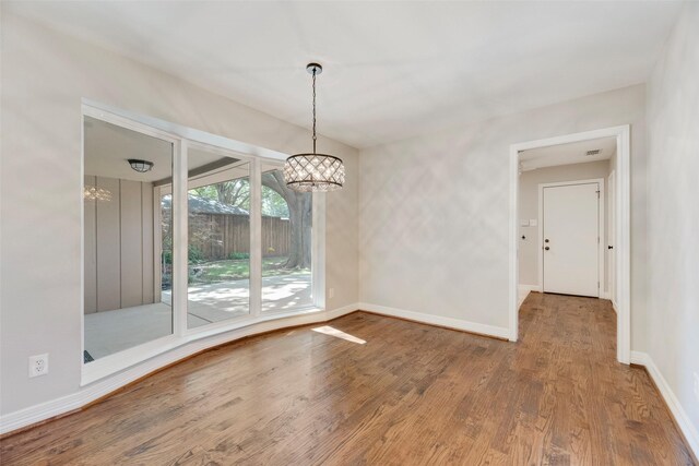 7324 Heathermore Dr, Dallas, TX 75248 - unfurnished dining area with a chandelier, wood finished floors, and baseboards