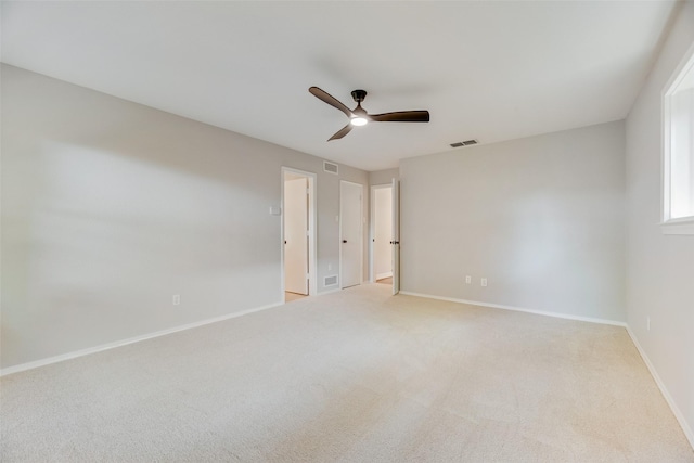 spare room with ceiling fan, light colored carpet, and baseboards