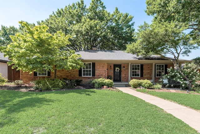 ranch-style home featuring a front lawn, brick siding, and a chimney