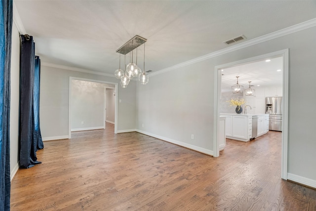 unfurnished dining area with a chandelier, light wood-style floors, ornamental molding, and baseboards