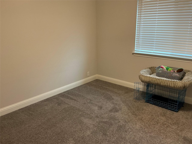 empty room with dark colored carpet and baseboards