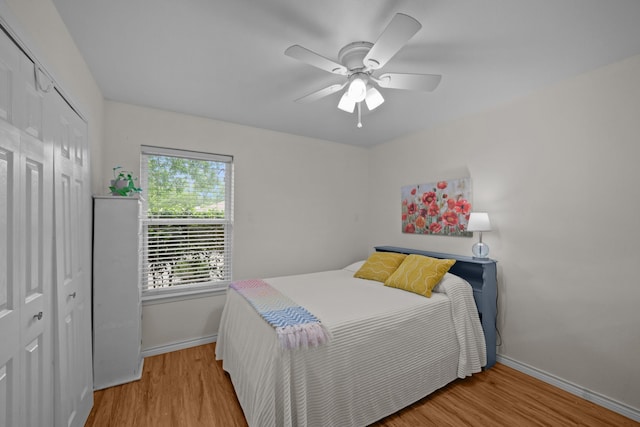 bedroom featuring a closet, baseboards, wood finished floors, and a ceiling fan