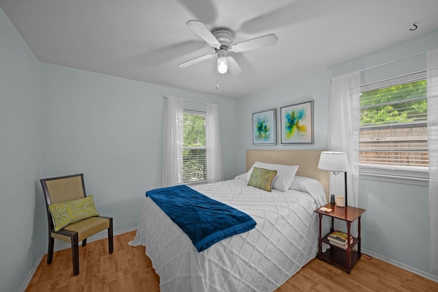 bedroom with baseboards, wood finished floors, and a ceiling fan