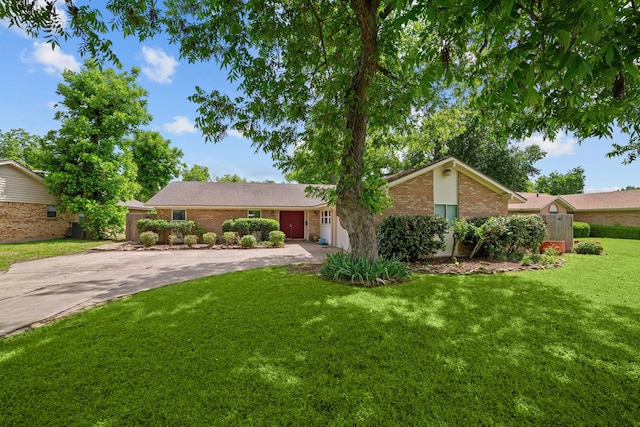 view of front of house featuring driveway, a front yard, a garage, and brick siding