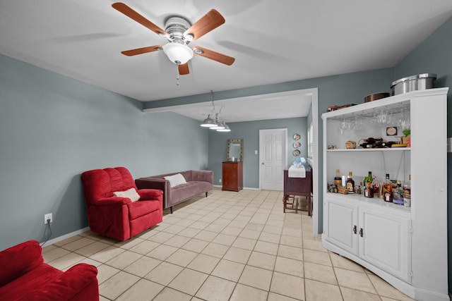 living room with a ceiling fan, baseboards, and light tile patterned floors