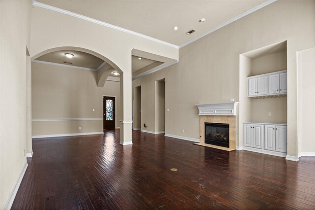 17 Wimbledon Ct, Heath, TX 75032 - unfurnished living room with arched walkways, hardwood / wood-style flooring, a tile fireplace, baseboards, and crown molding