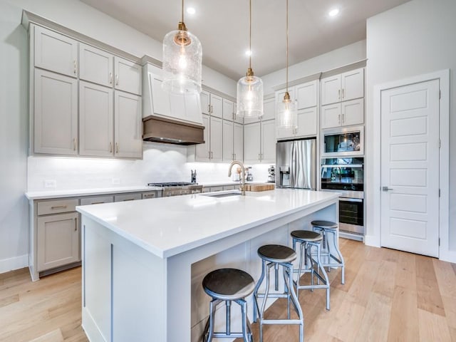 4208 Sunrise Ln, Celina, TX 75078 - kitchen featuring appliances with stainless steel finishes, light wood-style flooring, a sink, a breakfast bar area, and decorative light fixtures