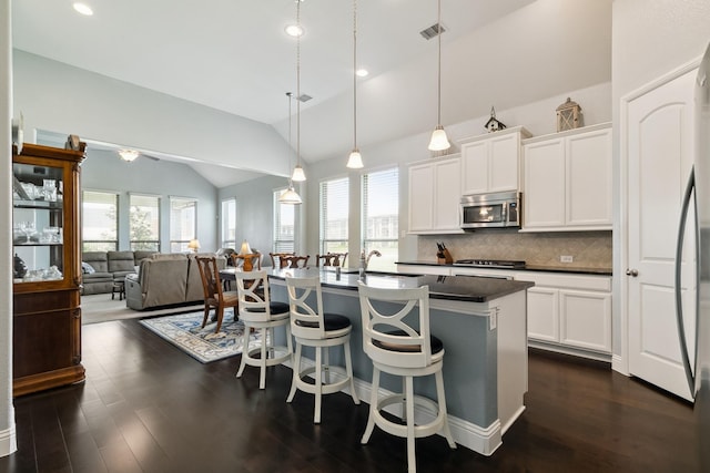 804 Countryside Way, Little Elm, TX 76227 - kitchen with stainless steel microwave, lofted ceiling, dark countertops, healthy amount of natural light, and a kitchen bar