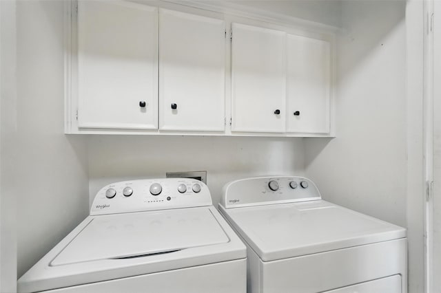 clothes washing area with washer and clothes dryer and cabinet space