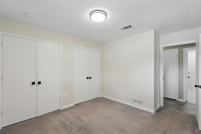 unfurnished bedroom with multiple closets, carpet floors, and baseboards