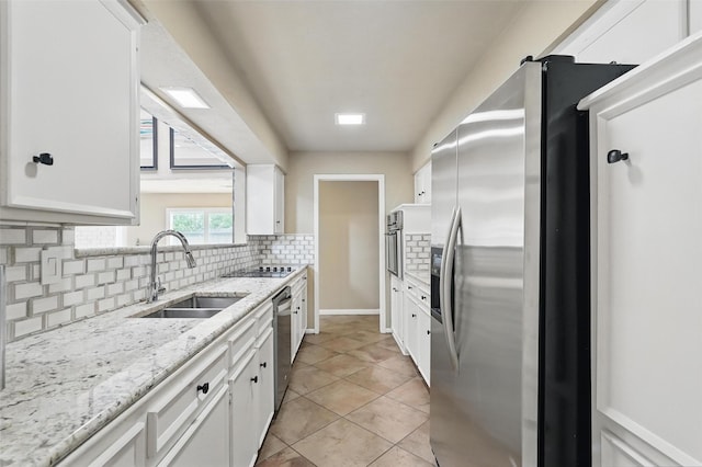 kitchen featuring stainless steel appliances, a sink, white cabinetry, and decorative backsplash