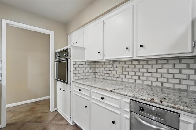 kitchen with wall oven, white cabinetry, tasteful backsplash, light stone countertops, and baseboards
