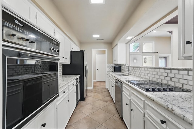 kitchen featuring black appliances, a sink, tasteful backsplash, and white cabinetry