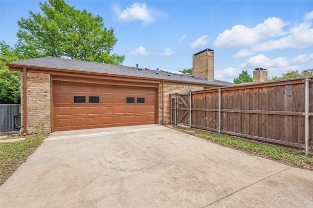 garage with fence, cooling unit, and driveway