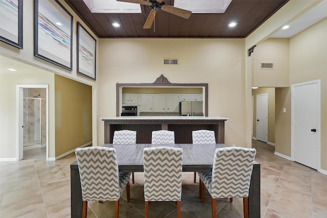 dining area with a towering ceiling, ceiling fan, a skylight, baseboards, and recessed lighting