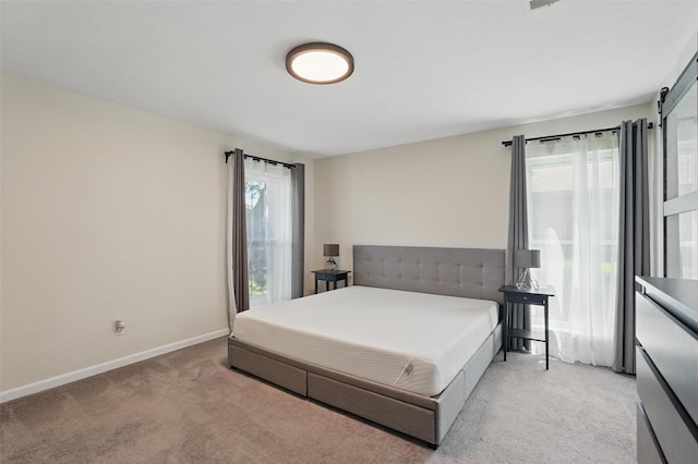 bedroom with light colored carpet, multiple windows, and baseboards