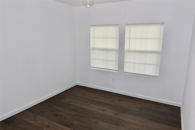 spare room with dark wood-type flooring and baseboards