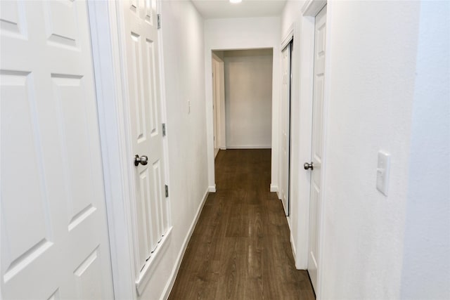 hallway featuring dark wood-type flooring and baseboards