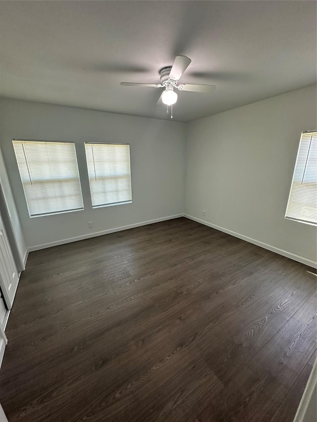 spare room featuring a ceiling fan, dark wood-type flooring, and baseboards