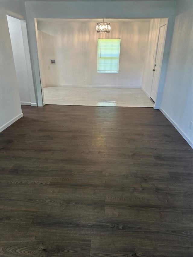 spare room with wood finished floors, baseboards, and a chandelier