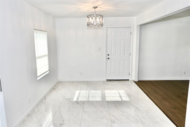unfurnished dining area with a chandelier, plenty of natural light, and baseboards