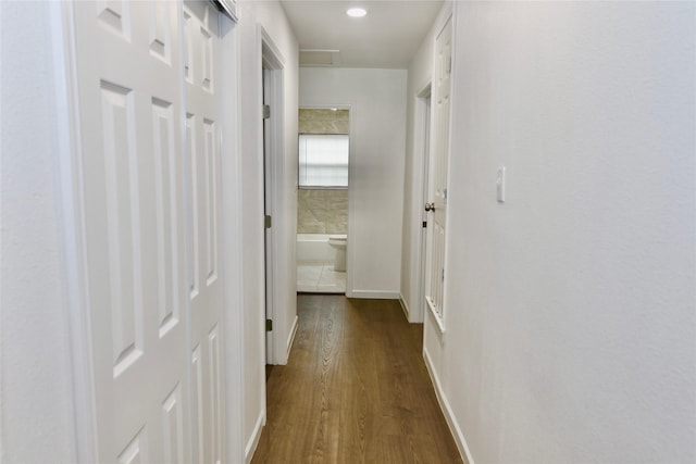 hall featuring dark wood-type flooring, baseboards, and recessed lighting