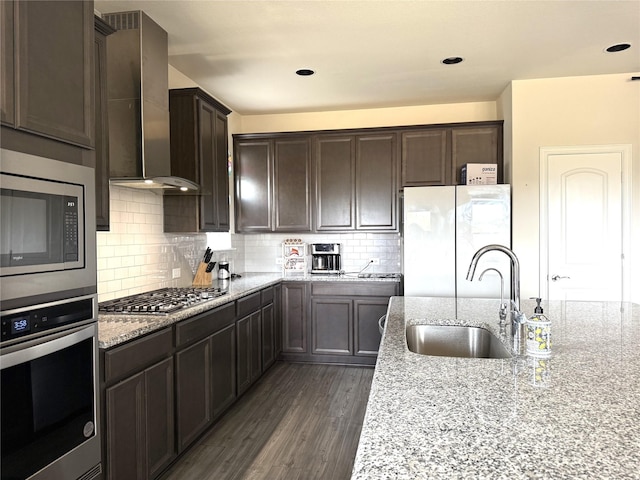 3340 Sorghum Way, Mckinney, TX 75071 - kitchen featuring stainless steel appliances, wall chimney exhaust hood, a sink, dark brown cabinets, and light stone countertops