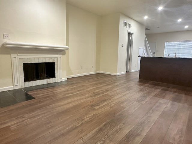 12921 Abrams Rd Unit 407, Dallas, TX 75243 - unfurnished living room with wood finished floors, recessed lighting, a tiled fireplace, stairway, and baseboards