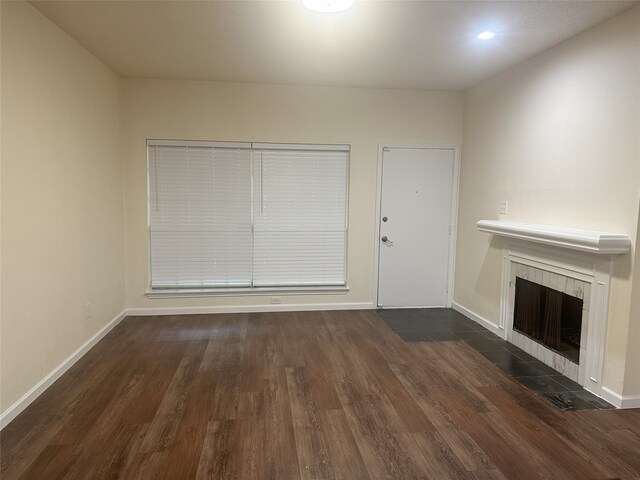 12921 Abrams Rd Unit 407, Dallas, TX 75243 - unfurnished living room with wood finished floors, a tiled fireplace, and baseboards