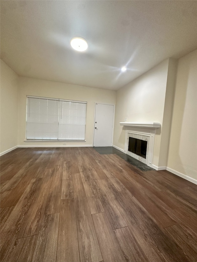 12921 Abrams Rd Unit 407, Dallas, TX 75243 - unfurnished living room featuring dark wood finished floors, a fireplace, and baseboards