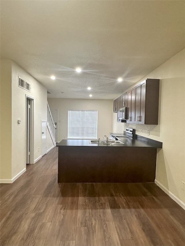 12921 Abrams Rd Unit 407, Dallas, TX 75243 - kitchen featuring stainless steel appliances, a peninsula, a sink, baseboards, and dark wood finished floors