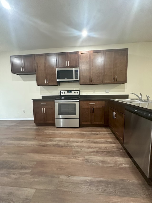 12921 Abrams Rd Unit 407, Dallas, TX 75243 - kitchen with appliances with stainless steel finishes, a sink, wood finished floors, and dark brown cabinets