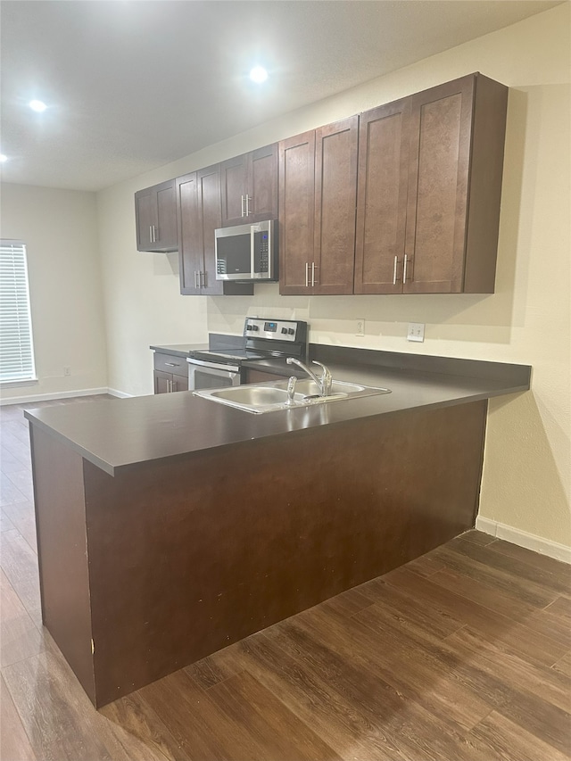 12921 Abrams Rd Unit 407, Dallas, TX 75243 - kitchen featuring appliances with stainless steel finishes, a sink, dark wood-style flooring, a peninsula, and dark countertops