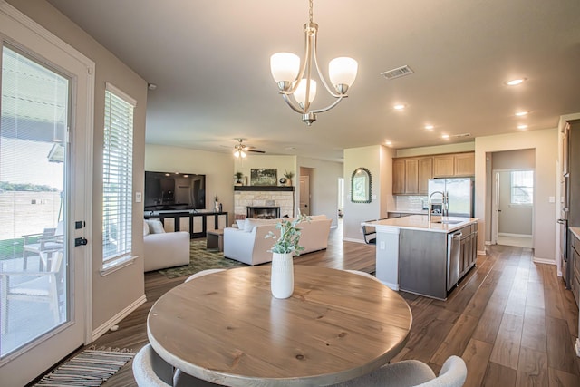 146 Chester Rd, Springtown, TX 76082 - dining area featuring baseboards, dark wood-style floors, a chandelier, a fireplace, and a ceiling fan