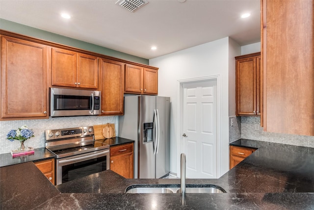 kitchen with stainless steel appliances, a sink, backsplash, recessed lighting, and brown cabinets