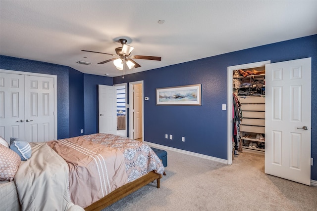 bedroom with a spacious closet, light carpet, baseboards, a ceiling fan, and a closet