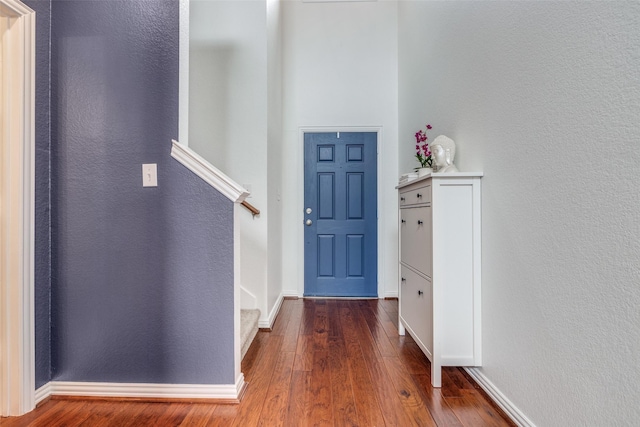 foyer featuring wood finished floors, baseboards, and a textured wall