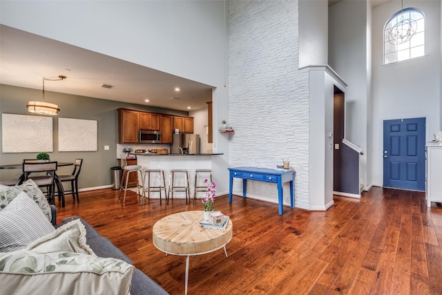 living area featuring a high ceiling, dark wood finished floors, and baseboards