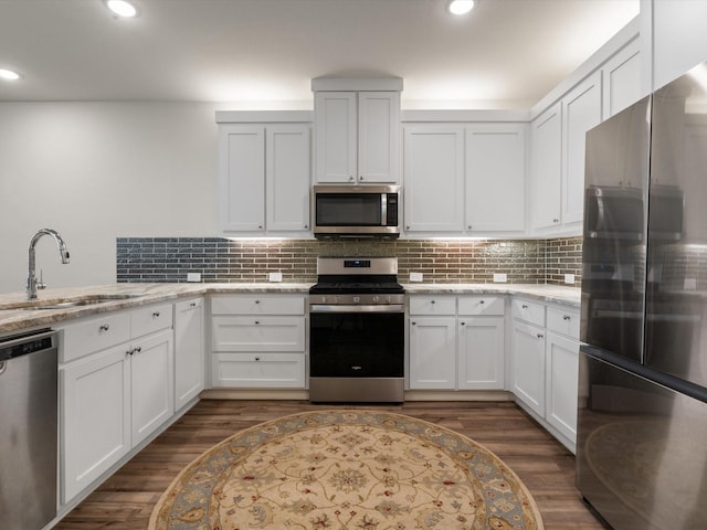 7335 Panicum Dr, Frisco, TX 75033 - kitchen featuring stainless steel appliances, a sink, dark wood-style flooring, white cabinetry, and recessed lighting