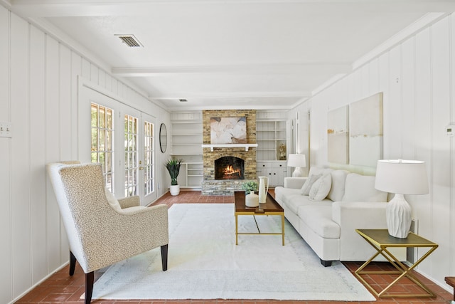 7609 Spring Valley Rd, Dallas, TX 75254 - living room featuring beamed ceiling, built in shelves, a fireplace, and a decorative wall