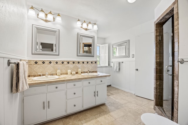 7609 Spring Valley Rd, Dallas, TX 75254 - bathroom with a stall shower, double vanity, a wainscoted wall, and tile patterned floors