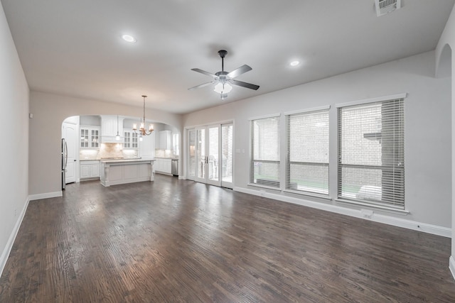 670 Bridge St, Coppell, TX 75019 - unfurnished living room featuring arched walkways, a ceiling fan, baseboards, a chandelier, and dark wood-style floors