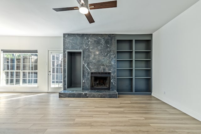 7525 Holly Hill Dr Unit 17, Dallas, TX 75231 - unfurnished living room featuring wood finished floors, a premium fireplace, a ceiling fan, and built in shelves