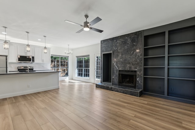 7525 Holly Hill Dr Unit 17, Dallas, TX 75231 - unfurnished living room featuring a sink, light wood finished floors, a chandelier, a ceiling fan, and a premium fireplace